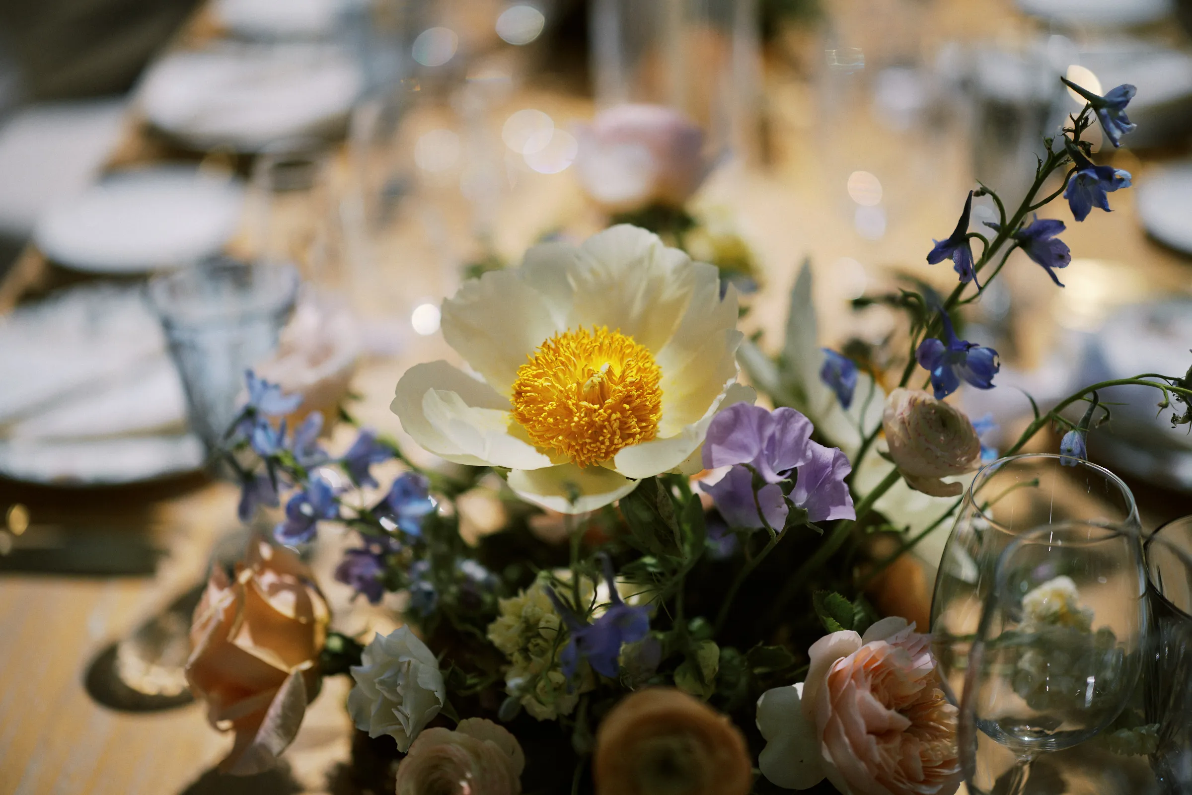 A centerpiece of peonies, ranunculus and delphinium on the reception table