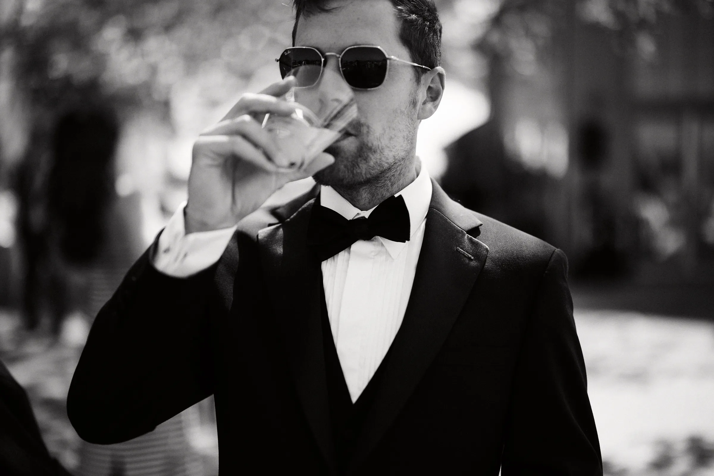 The groom with a drink in the afternoon sun, in black and white