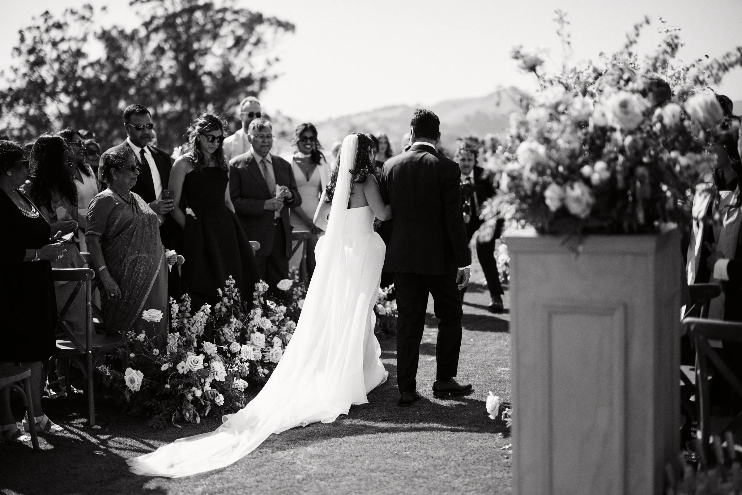 The couple walking the aisle past their guests, in black and white