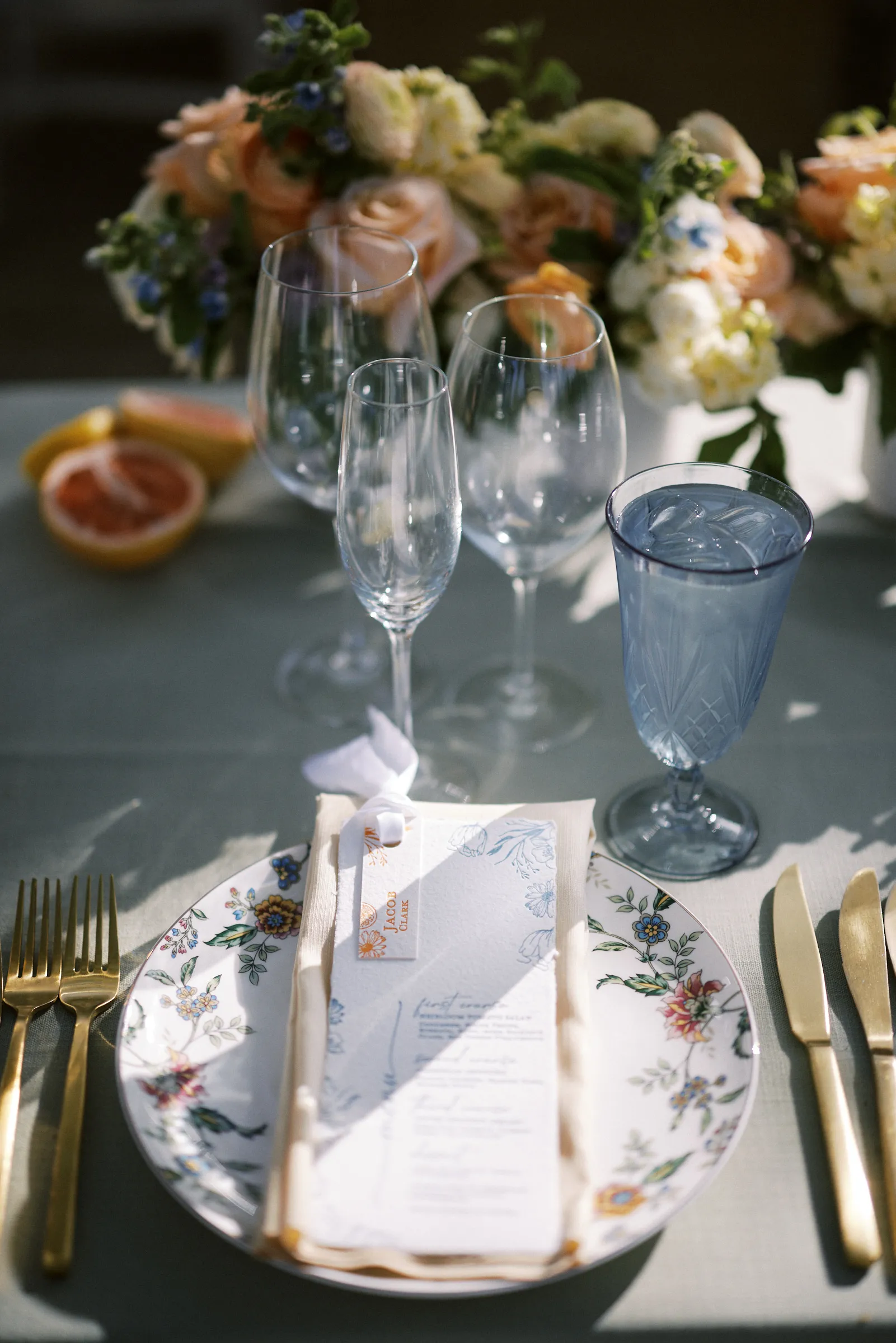 A place setting with a printed menu and blue glassware